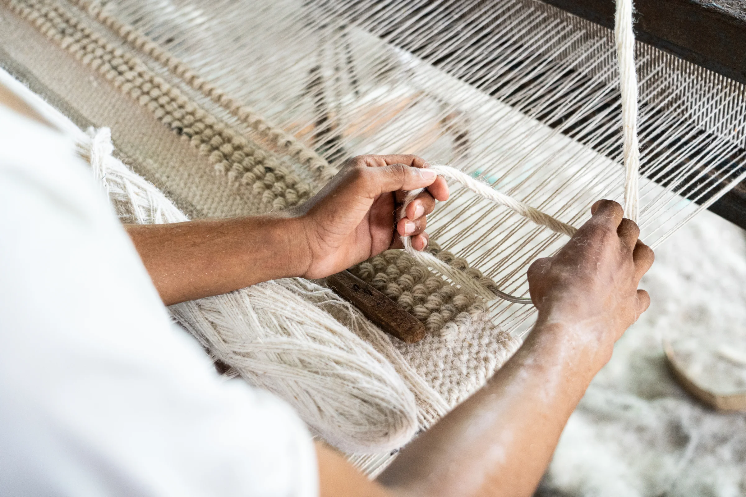 An artisan weaving an Exellica rug on the loom